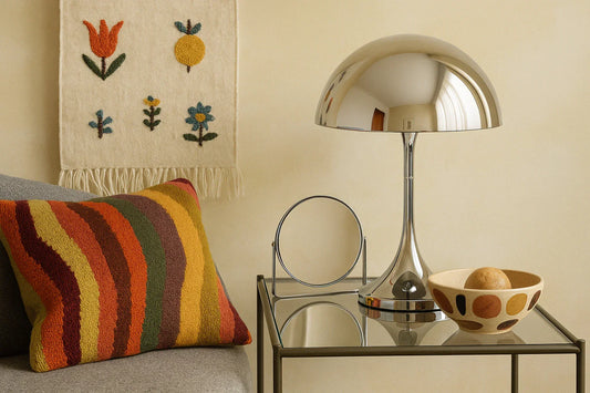 Chrome lamp and folk-inspired textiles in a cozy living room, blending reflective surfaces with handcrafted cushion and wall art.