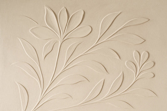 Textured plaster relief wall with sculpted botanical motifs and soft shadows in a calm, neutral-toned interior.