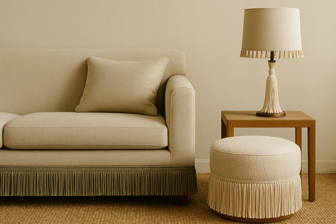 Neutral-toned interior with a beige fringed sofa, tasseled lamp, and ottoman in warm, soft light on a woven rug.