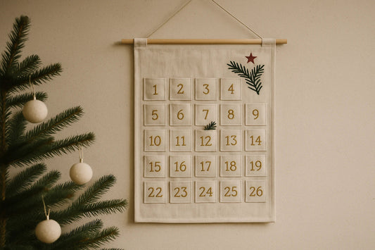 Fabric advent calendar hanging on a wall beside a small Christmas tree decorated with simple round ornaments.