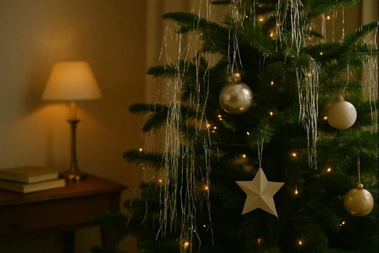 Christmas tree draped with silver icicle tinsel and simple ornaments, softly lit in a warm, quiet living room.